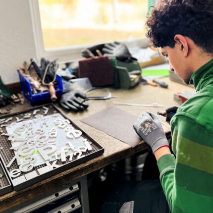 Mann bei Ziselierung von Buchstaben