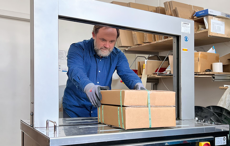Mann verpackt Paket an Verpackungsmaschine
